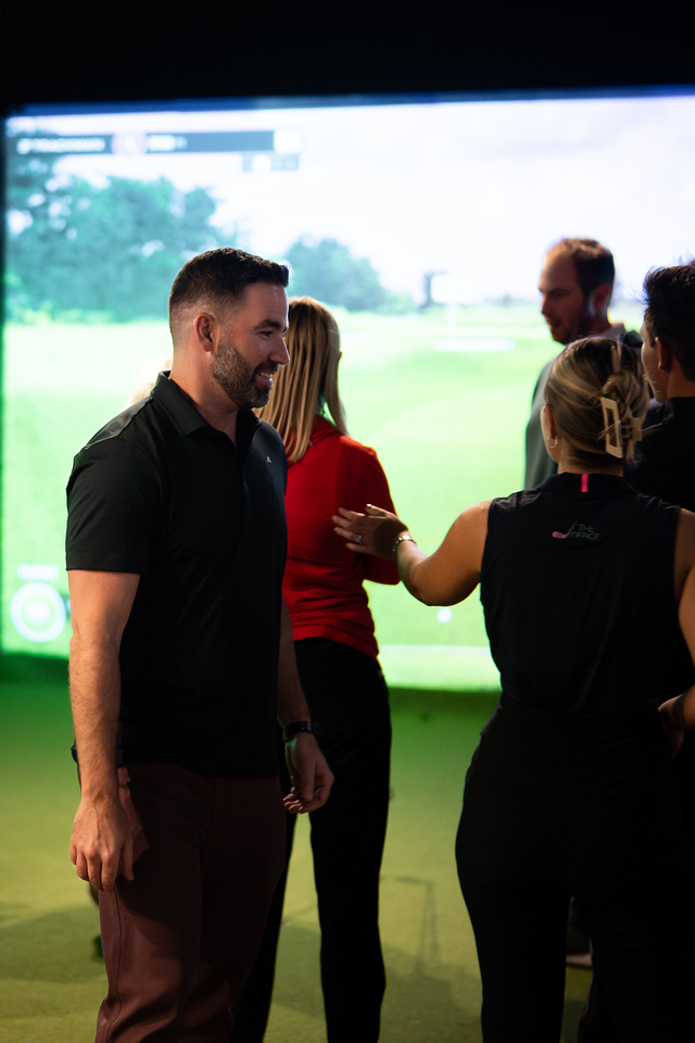 Members laughing together in a TrackMan bay in the evening
